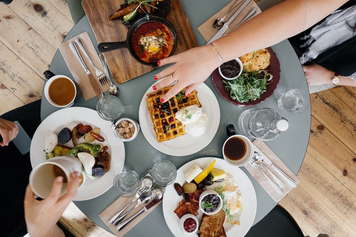 gedeckter Tisch mit viel gesunder Ernährung und zwei Hände die sich daran bedienen